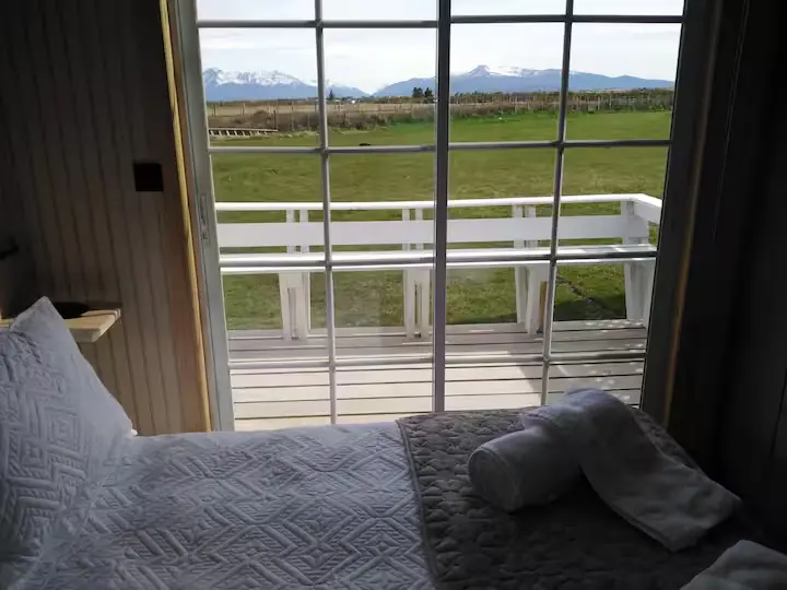 Dormitorio matrimonial de Cabaña Encanto con gran ventanal y vista directa a la cordillera y ventisqueros patagónicos
