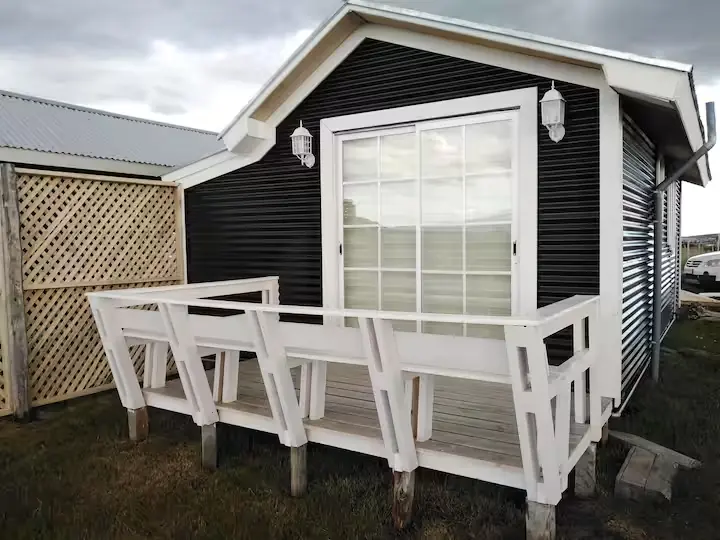 Fachada y terraza privada de madera de Cabaña Encanto con celosía divisoria de privacidad en Puerto Natales